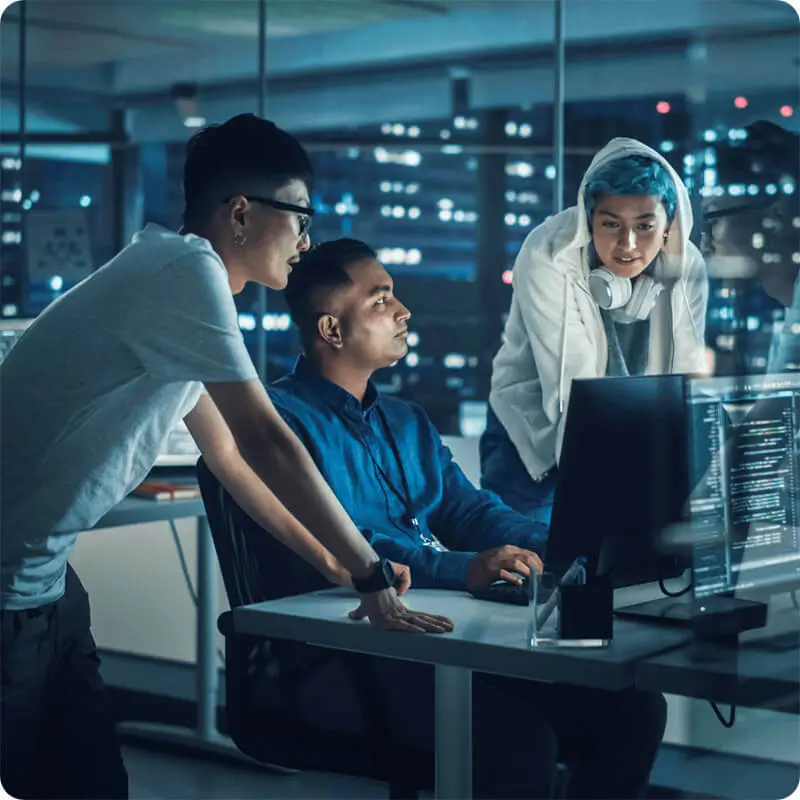 3 IT workers in a server room looking at a computer screen