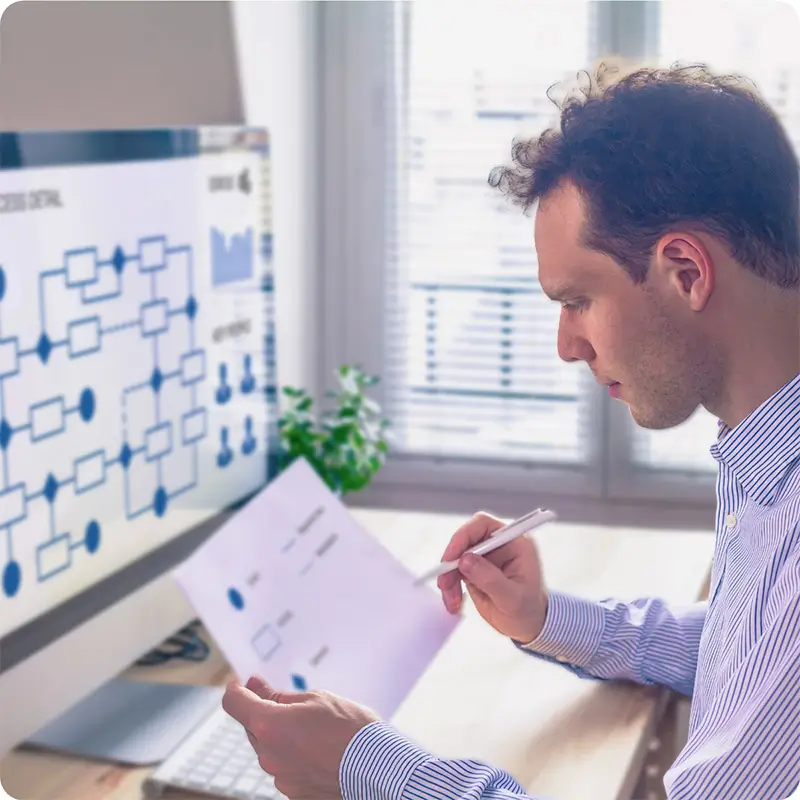 Businessman comparing printed chart with chart displayed on computer monitor