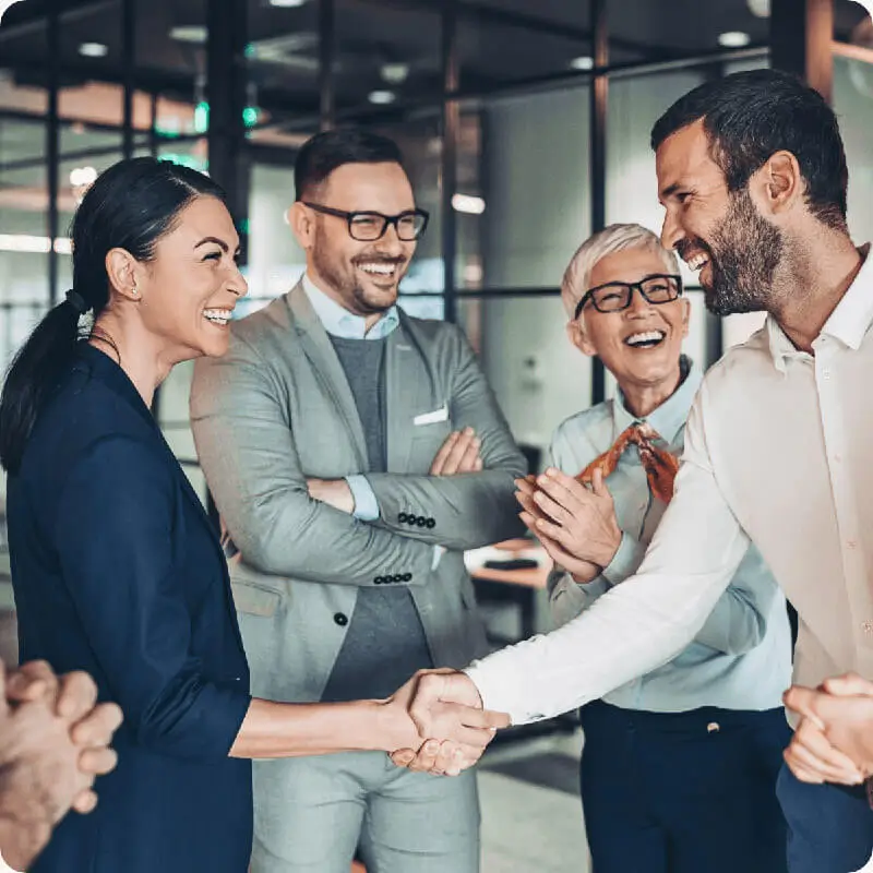 Four business partners shaking hands and celebrating.